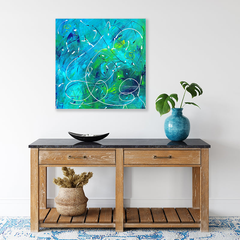 Abstract wall art print of swirling underwater currents in an aqua blue-green sea displayed in a tropical-style interior.