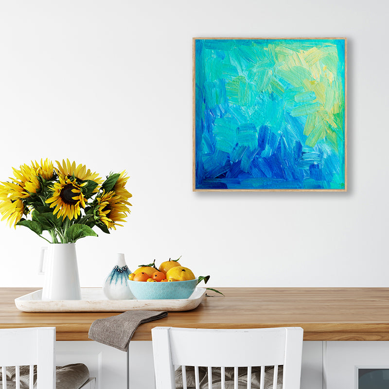 Abstract canvas art print with aqua, sapphire, and pale yellow hanging above a dining table in a coastal farmhouse interior.