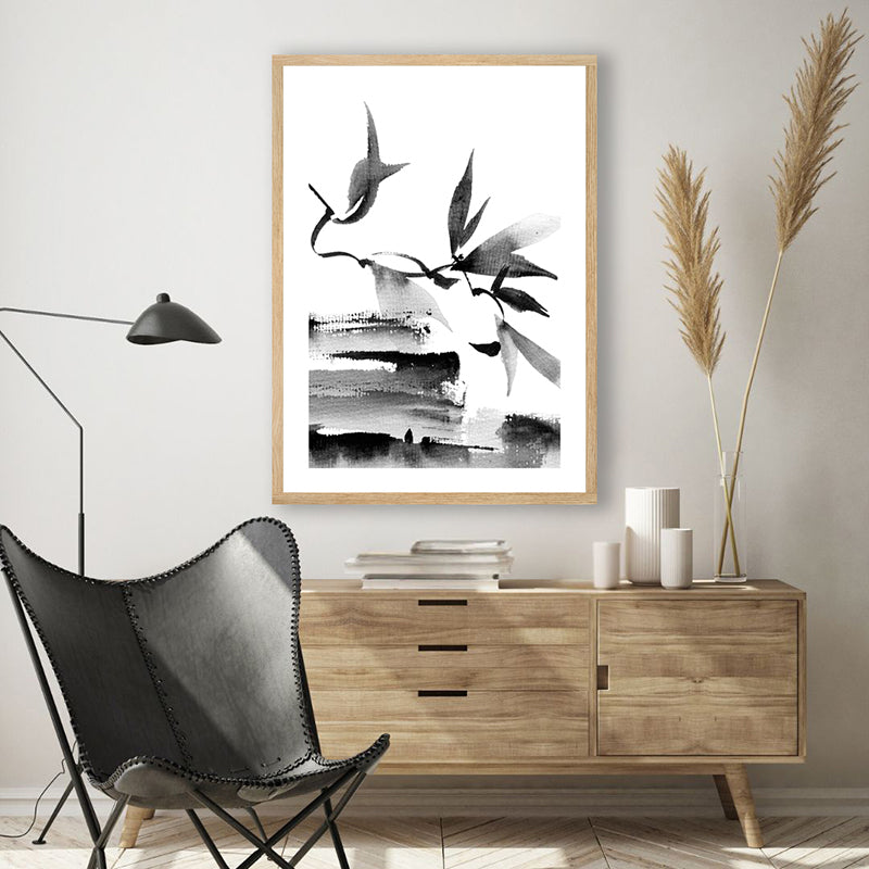 Black and white Japanese ink artwork of leaves and branches, in a modern, minimalist room.