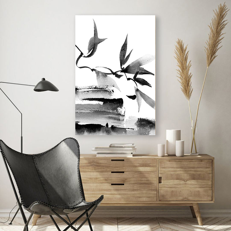 Black and white Japanese ink canvas art print of leaves and branches, in a modern, minimalist room.